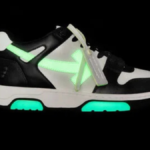A profile view of the Off-White "Out Of Office" (OOO) sneaker in a black and white colorway featuring neon green glow-in-the-dark accents on the arrow motif and sole.