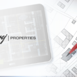 A digital tablet displaying a detailed architectural floor plan with the Godrej Properties logo, positioned next to a physical site map being marked with a red pen.