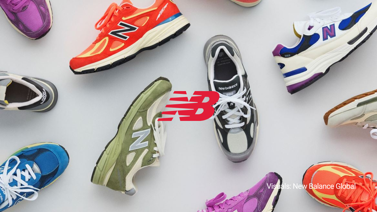 A top-down lifestyle arrangement of the New Balance Made in USA Spring/Summer 2026 footwear collection featuring vibrant purple, orange, olive green, and blue 99X series sneakers surrounding a red New Balance logo.