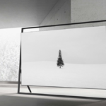 Samsung 130-inch Micro RGB display featuring the Vision AI Companion (VAC) in a minimalist "Timeless Frame" floor stand, showcasing a black and white winter landscape in a modern concrete room.