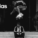 Black and white high-angle shot featuring Samuel L. Jackson seated on stone steps while skateboarding legend Tyshawn Jones performs an aerial trick above him, both wearing adidas Superstars.