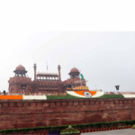 The Red Fort in Delhi decorated with the Indian Tricolour and floral arrangements for a high-level national event, symbolizing the launch of the DAP-2026 defense manifesto.