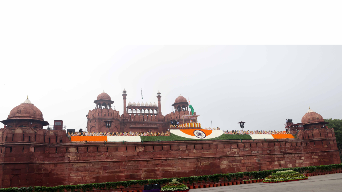 The Red Fort in Delhi decorated with the Indian Tricolour and floral arrangements for a high-level national event, symbolizing the launch of the DAP-2026 defense manifesto.