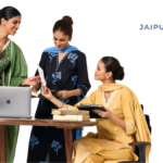 Three women in Jaipur Kurti ethnic wear working in a modern office setting.