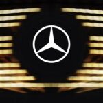 The iconic Mercedes-Benz three-pointed star logo set against a backdrop of illuminated horizontal slats, representing the upcoming 2026 V-Class.