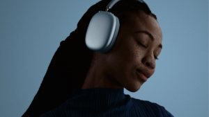 A woman wearing the blue AirPods Max 2 headphones with her eyes closed, demonstrating the immersive Active Noise Cancellat...