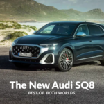 Front-three-quarter view of the new Audi SQ8 in a dark metallic shade parked on a coastal road, showcasing the V8 performance SUV's matte silver grille and quad-exhaust silhouette.