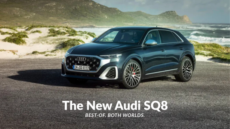 Front-three-quarter view of the new Audi SQ8 in a dark metallic shade parked on a coastal road, showcasing the V8 performance SUV's matte silver grille and quad-exhaust silhouette.