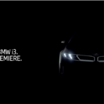 Official teaser image of the new BMW i3 Neue Klasse electric sedan showing illuminated signature LED headlights and wide kidney grille silhouette against a black background for the March 2026 premiere.
