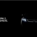 Official teaser image of the new BMW i3 Neue Klasse electric sedan showing illuminated signature LED headlights and wide k...