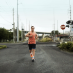 Ironman athlete Chris Nikic running on a city street wearing the orange adidas Supernova Rise 3 Adaptive performance shoes.