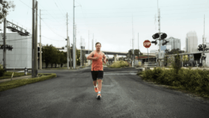 Ironman athlete Chris Nikic running on a city street wearing the orange adidas Supernova Rise 3 Adaptive performance shoes.