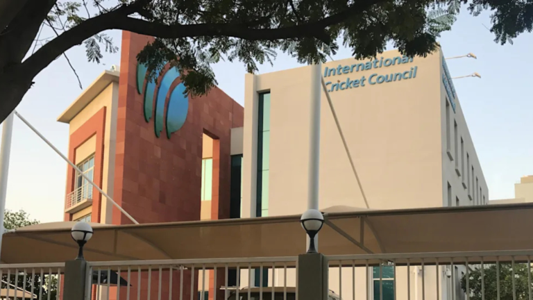 The exterior of the International Cricket Council (ICC) headquarters building in Dubai, featuring the prominent green and blue ICC logo and clear corporate branding.
