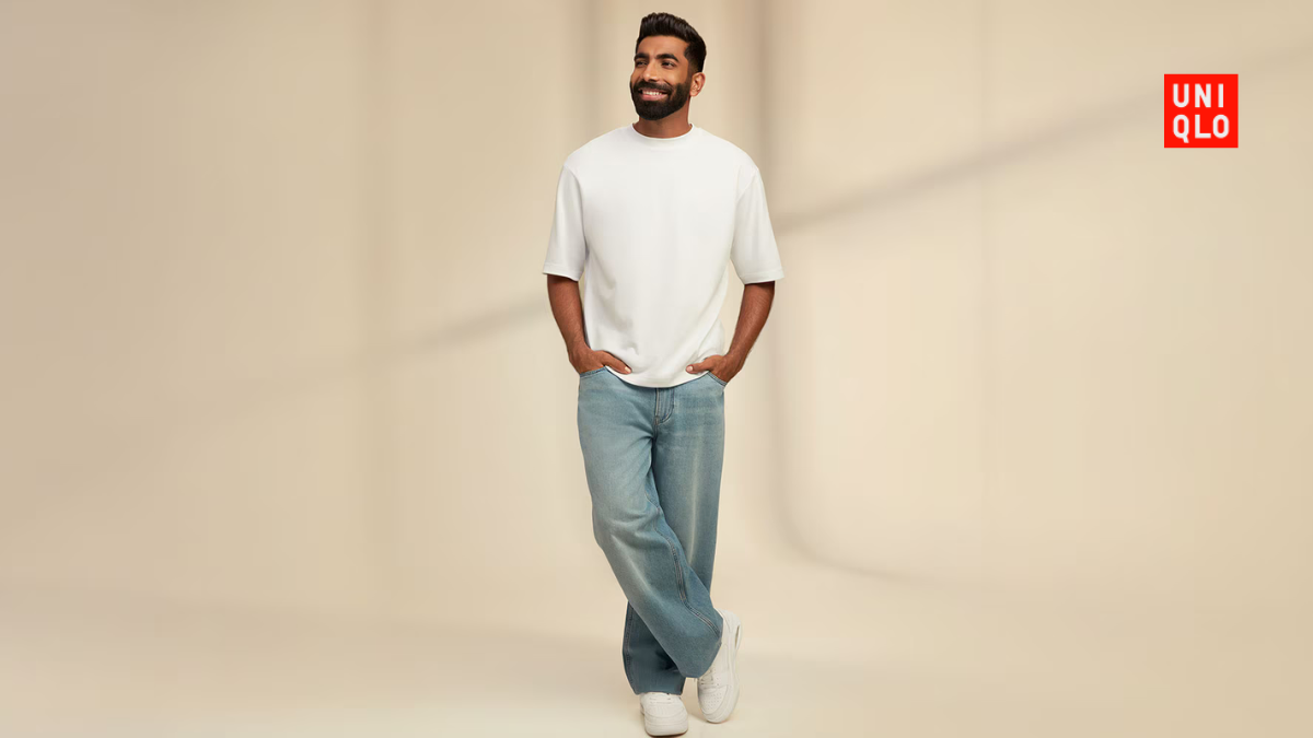 Jasprit Bumrah posing in a white Uniqlo AIRism Cotton Oversized T-shirt and relaxed light blue jeans with white sneakers.