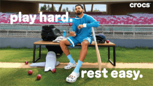 Indian cricketer KL Rahul sitting in a stadium wearing white Crocs Classic Clogs with Jibbitz charms for the Play Hard Res...