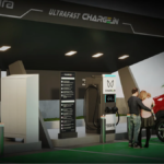 A family standing by a red electric car at a premium Mahindra Charge_iN station featuring 180kW ultra-fast dual-gun EV chargers under a modern canopy.