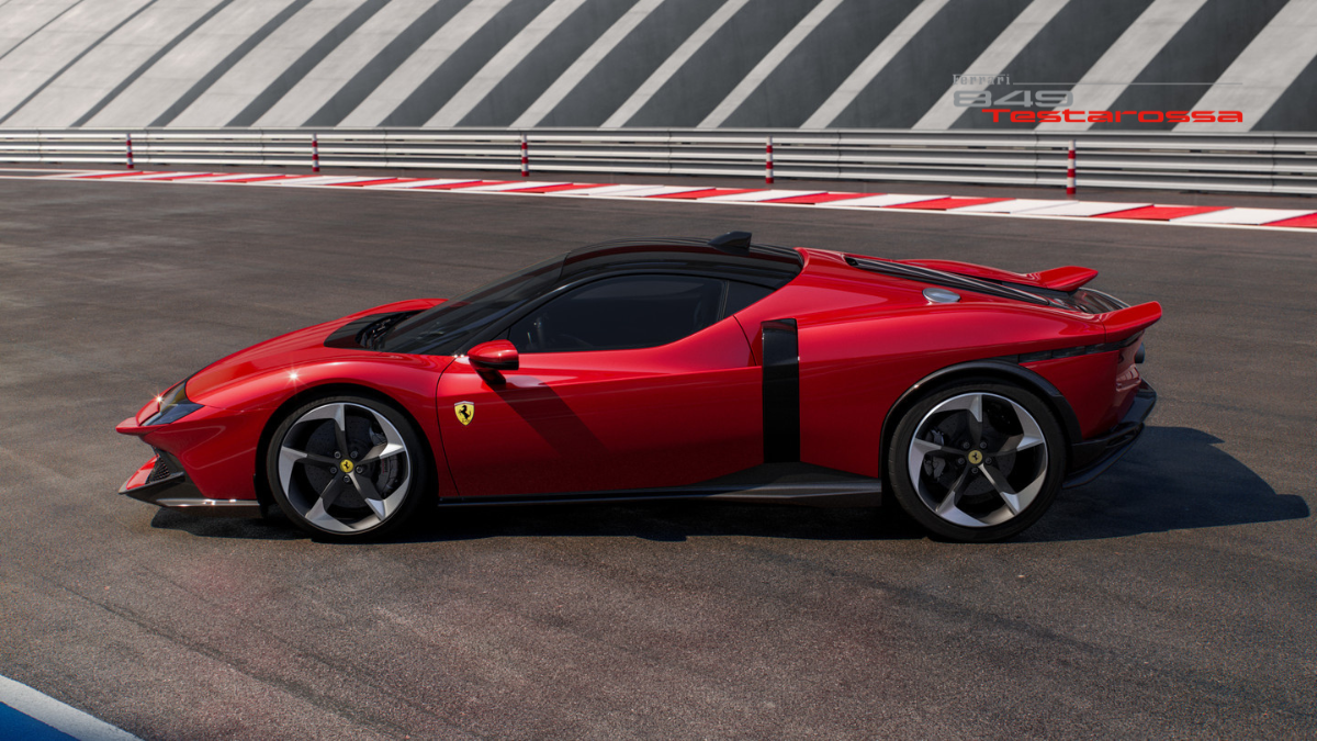 The Legend Reborn: Ferrari 849 Testarossa Officially Debuts in India 4 Side profile view of a red Ferrari 849 Testarossa concept car parked on a professional racing circuit with black and white striped barriers.