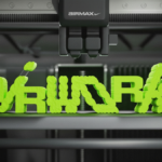 A close-up of an industrial 3D printer nozzle manufacturing the neon green "AIR WORKS" logo for the Nike design program.