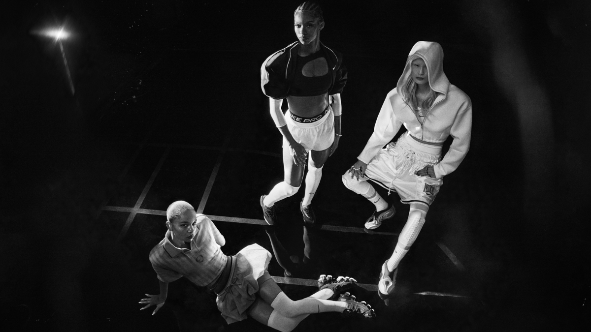 Nike First Sight Collection: India Release Date, Price, and the New Nike.in Era 1 Three women posing in a high-contrast, noir-style studio setting wearing the Nike First Sight collection, including sporty cropped jackets, shorts, and futuristic footwear.