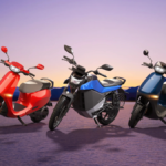 A red Ola S1 X scooter, a blue and grey Roadster X motorcycle, and a blue S1 X scooter parked against a sunset horizon.