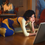 A woman lying on a living room floor using the detached 27-inch Samsung Movingstyle display with its built-in kickstand.