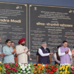 Prime Minister Narendra Modi on stage with Nitin Gadkari and Pushkar Singh Dhami inaugurating the 6-lane Delhi-Dehradun Ec...