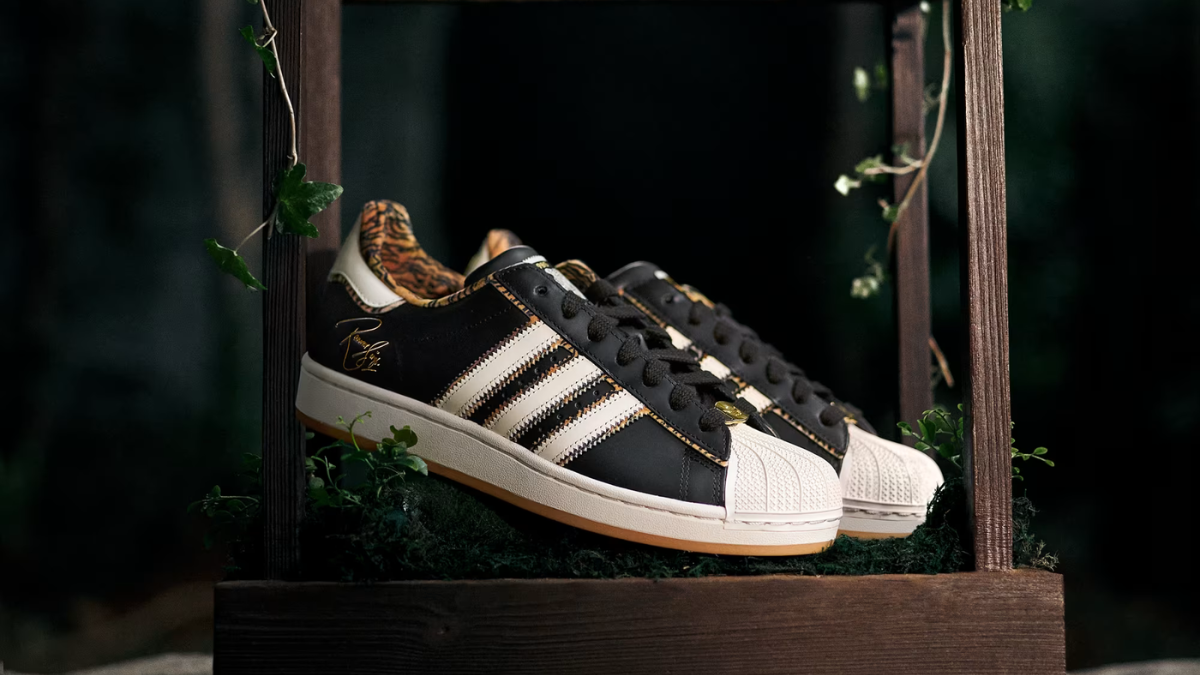 Black leather sneakers on a dark wooden frame with a gold Ranveer Singh signature and tiger-print collar in India.
