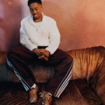 Myles Lewis-Skelly on a sofa wearing an off-white jacket and snake-print adidas Predator boots for the India campaign.