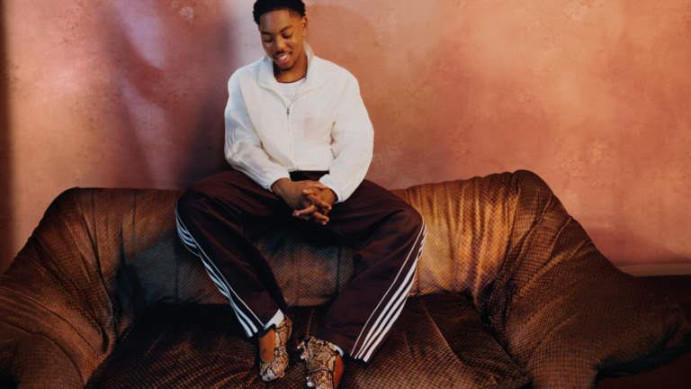 Myles Lewis-Skelly on a sofa wearing an off-white jacket and snake-print adidas Predator boots for the India campaign.