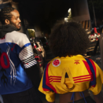 Three fans viewed from behind in a traffic jam wearing vintage-style adidas away jerseys with numbers 10 and 96 and federa...