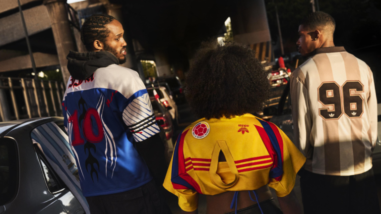 Three fans viewed from behind in a traffic jam wearing vintage-style adidas away jerseys with numbers 10 and 96 and federa...