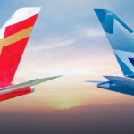 Air India and WestJet airplane tail fins facing each other against a sunset sky for their India-Canada partnership.