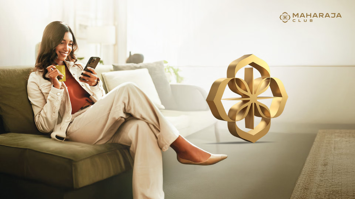 A woman smiling while checking her Maharaja Club points on a smartphone and holding a gold tier membership card next to a golden 3D logo.