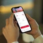 A user holding a smartphone with the high-rated Air India mobile app open to the flight booking screen for Kochi to Dubai.