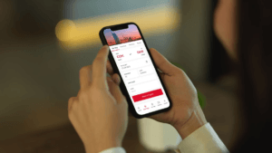 A user holding a smartphone with the high-rated Air India mobile app open to the flight booking screen for Kochi to Dubai.