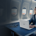 Man in a suit using a white ASUS ExpertBook Ultra on a plane table, highlighting its premium mobile business design.