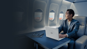 Man in a suit using a white ASUS ExpertBook Ultra on a plane table, highlighting its premium mobile business design.
