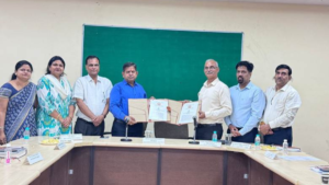 Two men holding signed documents with faculty members standing nearby for the Ayurveda innovation partnership in India.