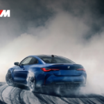 A high-performance blue BMW M4 Competition drifting on a track featuring the official BMW M Drift Academy Class of 2026 branding.
