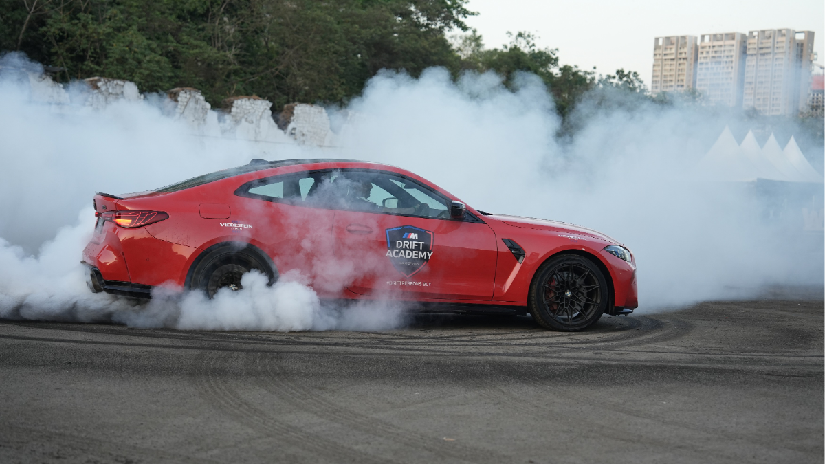 BMW M Drift Academy 2026 India: Dates, Cities, Fees and How to Enrol 2 Side profile of a red BMW M4 Competition performing a high-angle drift with thick tire smoke at a BMW M Drift Academy event.
