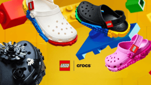 A promotional group shot of the Crocs x LEGO collection featuring white, black, and pink clogs with LEGO brick-inspired mi...