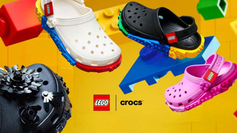 A promotional group shot of the Crocs x LEGO collection featuring white, black, and pink clogs with LEGO brick-inspired mi...