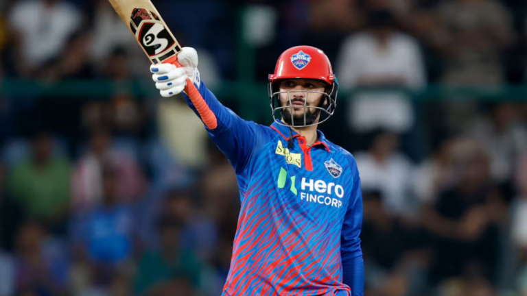 TATA IPL 2026 Match 8: Sameer Rizvi & Mukesh Kumar Power Delhi to 2nd Win in DC vs MI 1 A Delhi Capitals cricket player celebrating a milestone on the field, raising an SS cricket bat to acknowledge the crowd. He wears a red helmet and blue/orange team jersey with 'Hero FINCORP' branding during a TATA IPL match.