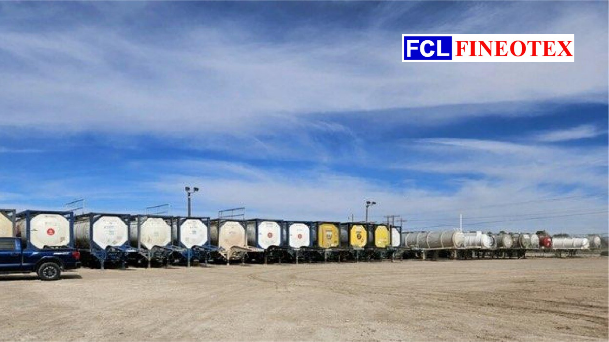 A fleet of industrial chemical storage tanks and ISO containers on trailers in a logistics yard branded with FCL Fineotex.