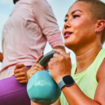 Woman holding a kettlebell outdoors wearing a Fitbit smartwatch for a personalised workout in India.