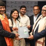 Five individuals exchanging a blue IHG folder in front of an IHG and TGH&R banner during a signing in India.