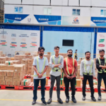 Five staff in safety vests standing by stacked boxes inside an HUL Delhi Nano DC facility in India.