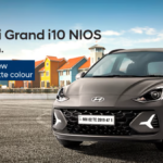 Front three-quarter view of the new Hyundai Grand i10 NIOS VIBE Edition in Titan Grey Matte parked against a coastal backd...