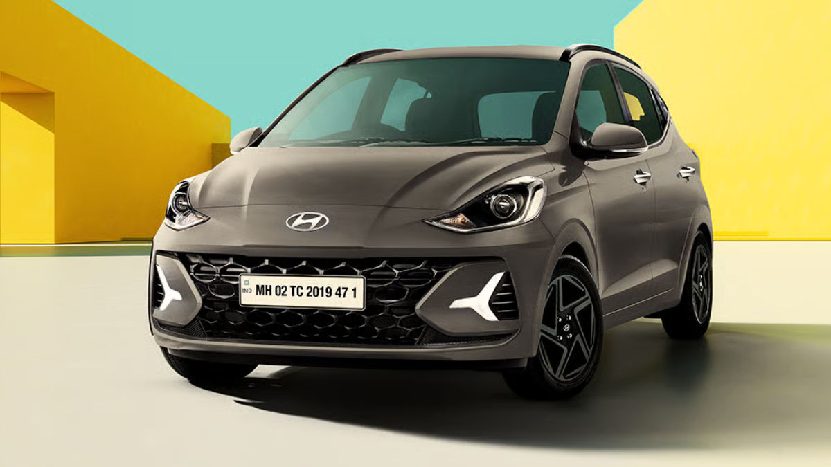 A studio shot of the Hyundai Grand i10 NIOS VIBE Edition showcasing the aggressive front grille, projector headlamps, and black-painted alloy wheels.