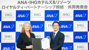 IHG and ANA executives holding a signed document against a branded backdrop for their India loyalty partnership.